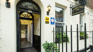 The exterior of Marble Arch Inn, featuring a black arch entrance, a signboard with the inn's name, and a small sign indicating AA accommodation. - Marble Arch Inn Hotel (London)