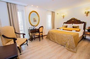 Una habitación de hotel con una cama grande, una silla, un escritorio y un espejo.