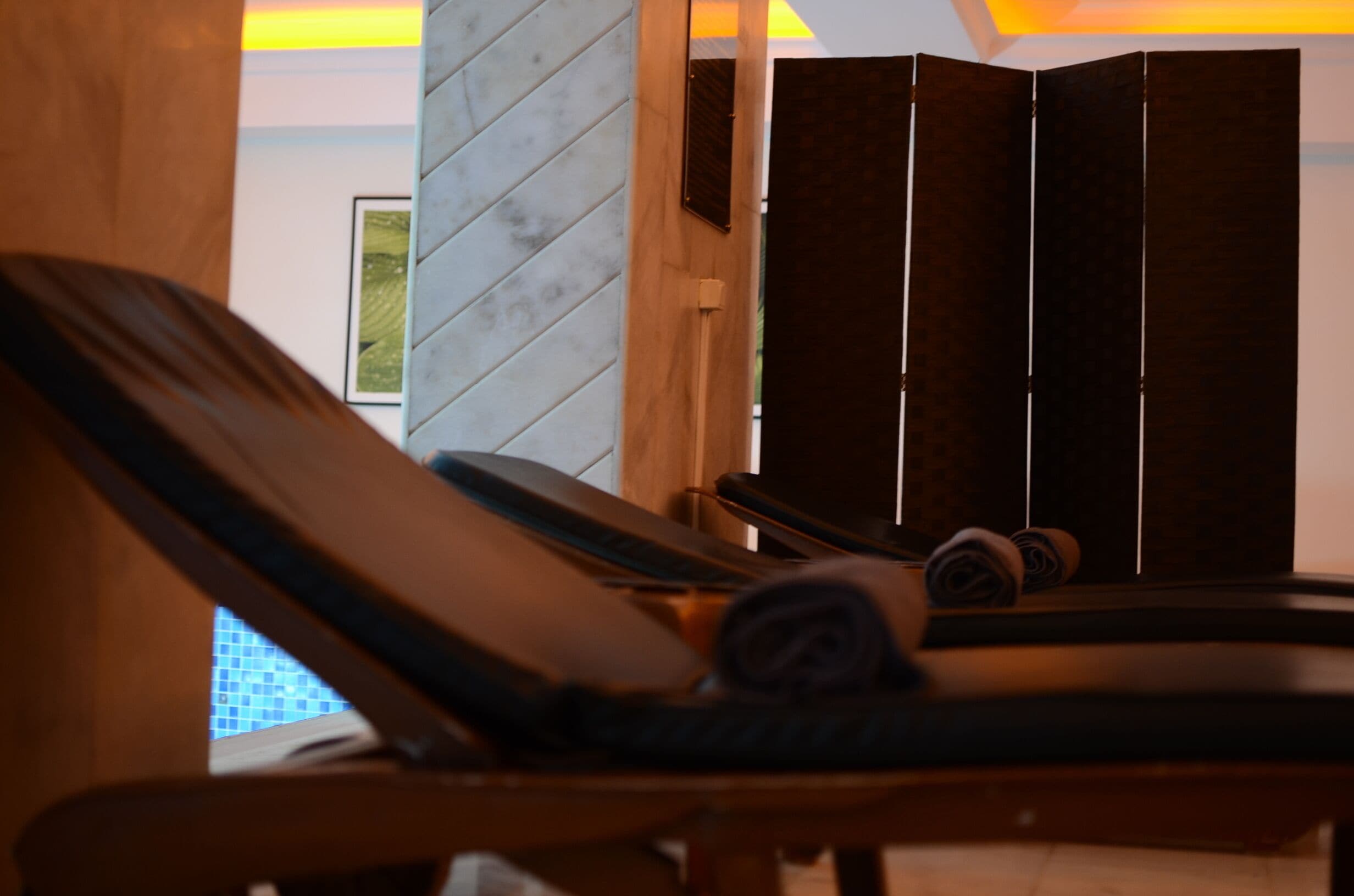 A room with a wooden chair, a dark-colored sofa, and a partition with vertical slats.
