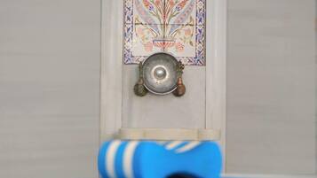 A blue yoga mat on a white floor, a decorative tile with a floral pattern, and a metal bowl hanging on a wall.