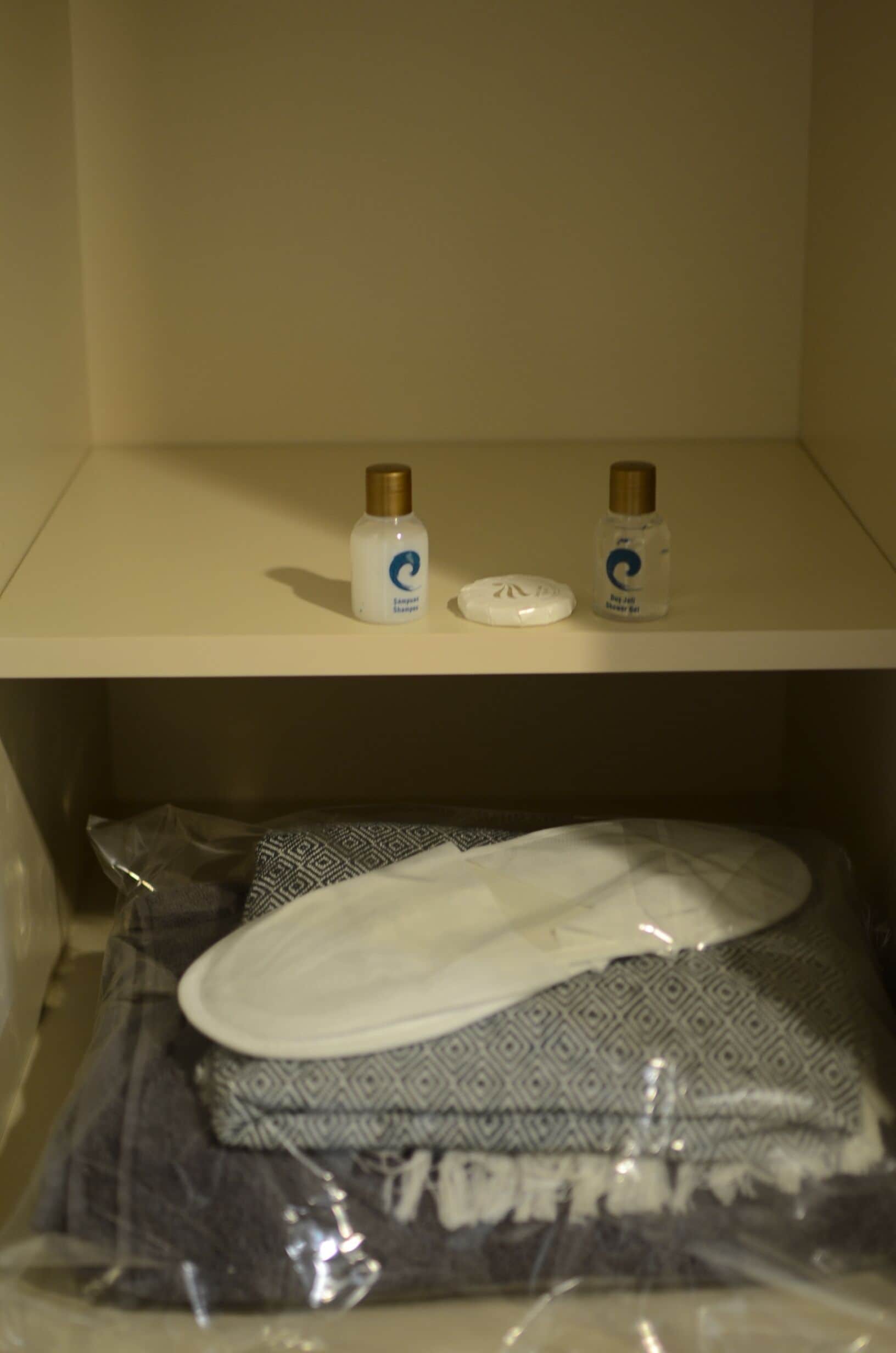 Un estante de baño con dos botellas de champú y una toalla blanca.