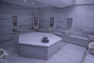 Un baño moderno con una bañera cuadrada en el centro, varios lavamanos y azulejos decorativos en las paredes.