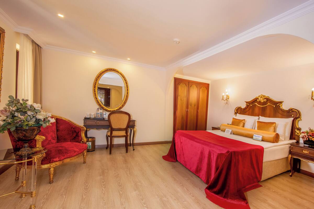 Habitación de hotel con una cama grande, un escritorio, una silla, un espejo y un cuadro en la pared.