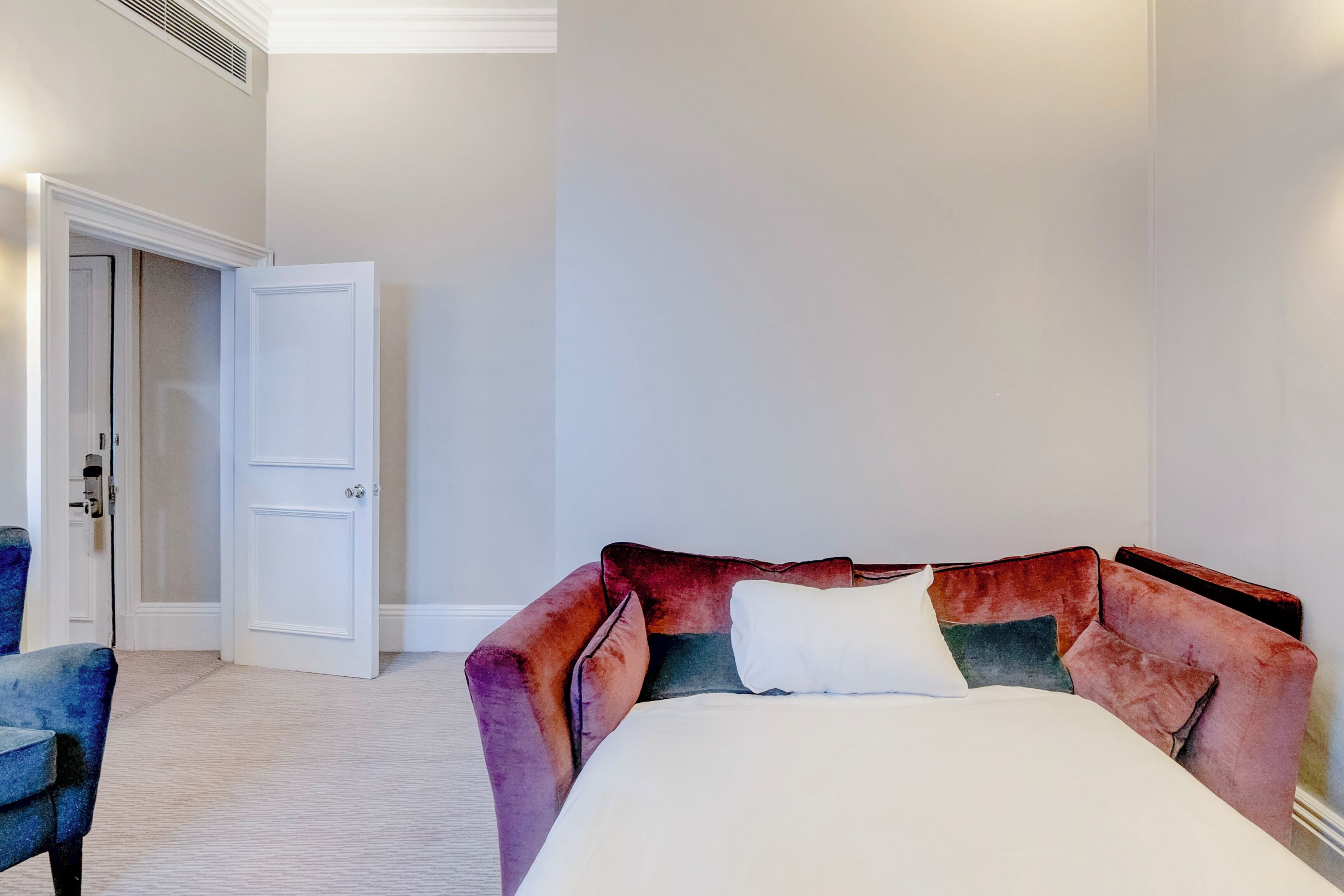 A bedroom with a bed, a chair, and a door.