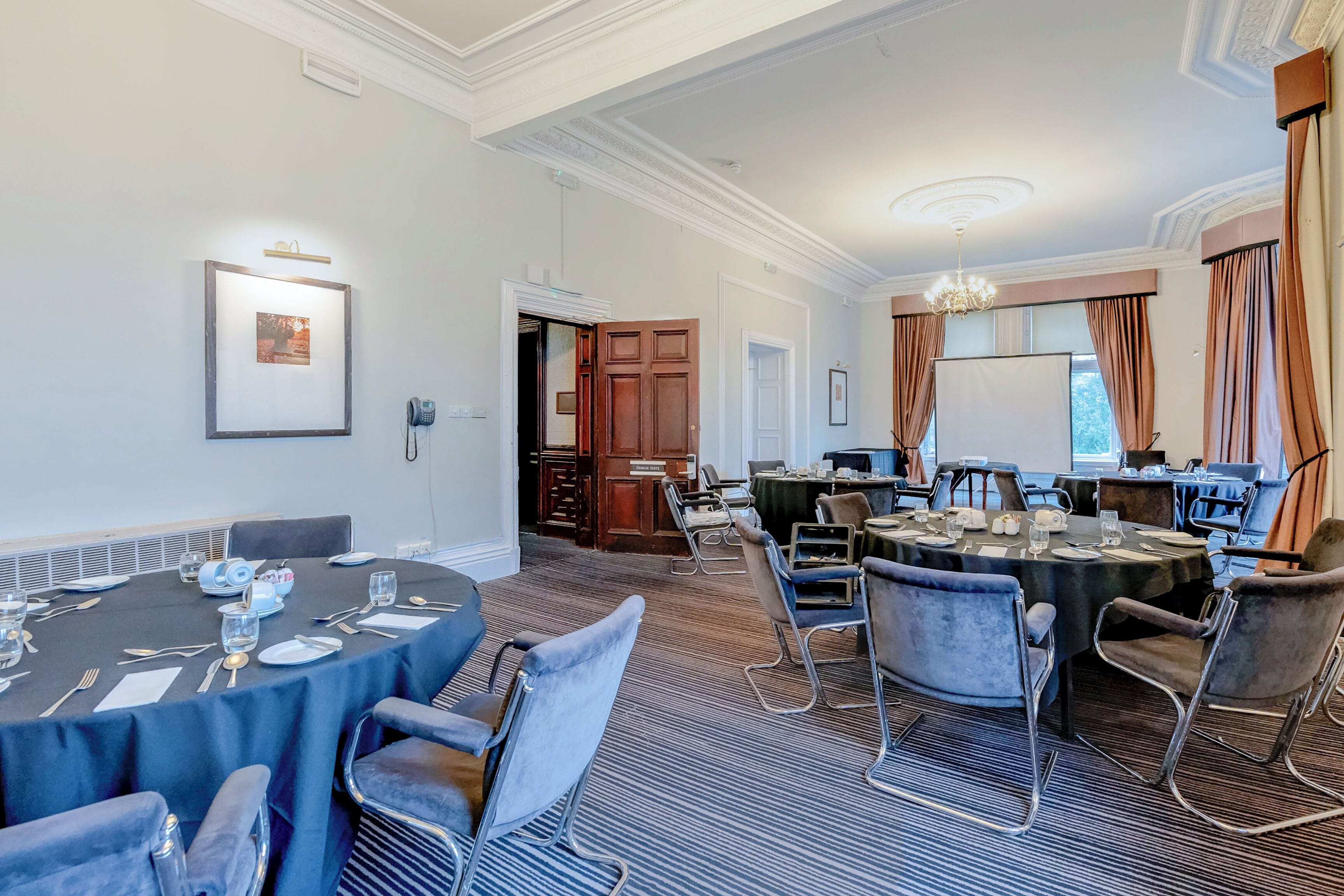 A conference room with round tables, chairs, and a chandelier.