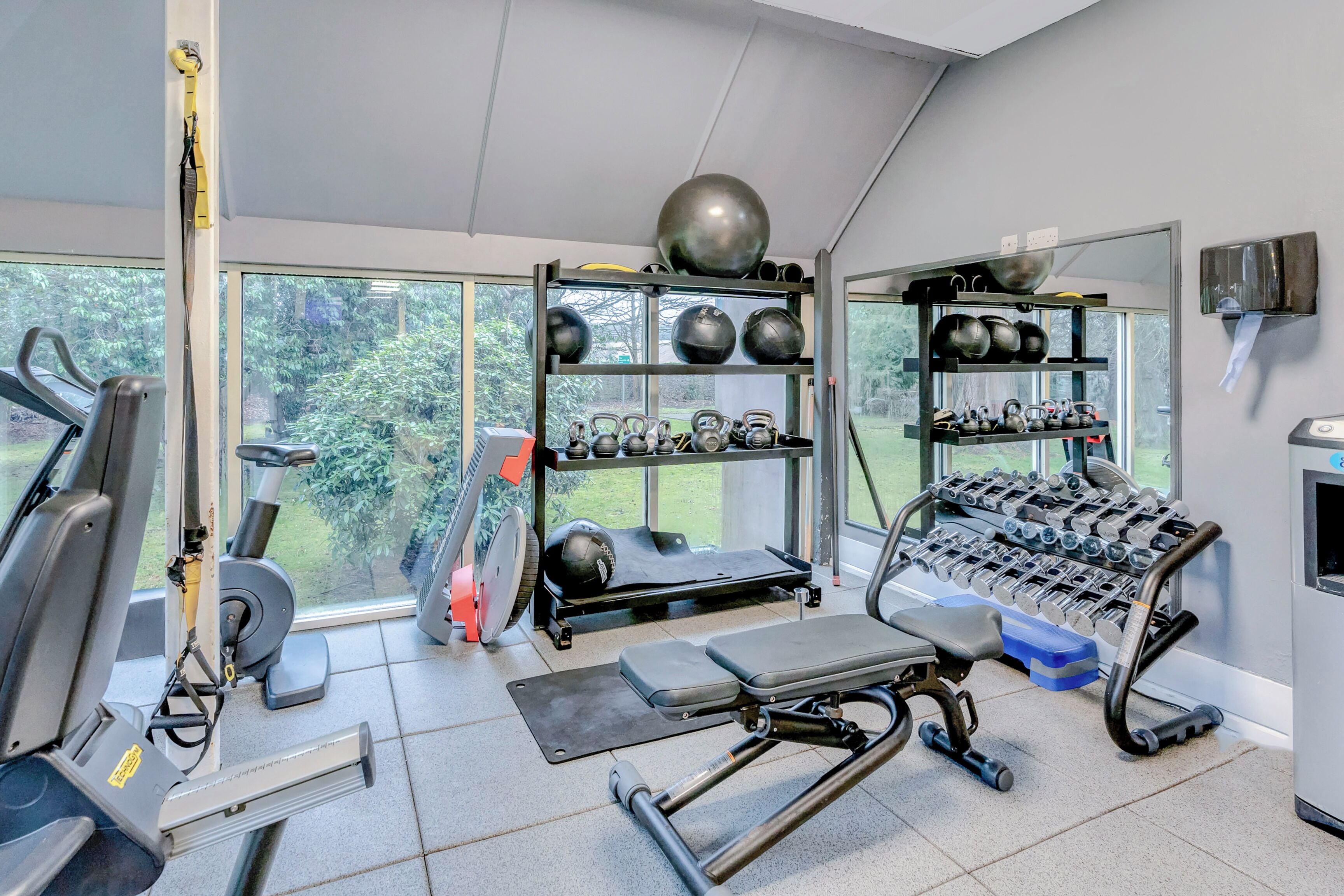 A gym with exercise equipment, kettlebells, and dumbbells.