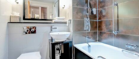 Un bagno moderno con un water bianco, un mobile lavabo nero con lavandino, uno specchio grande e uno spazio doccia.