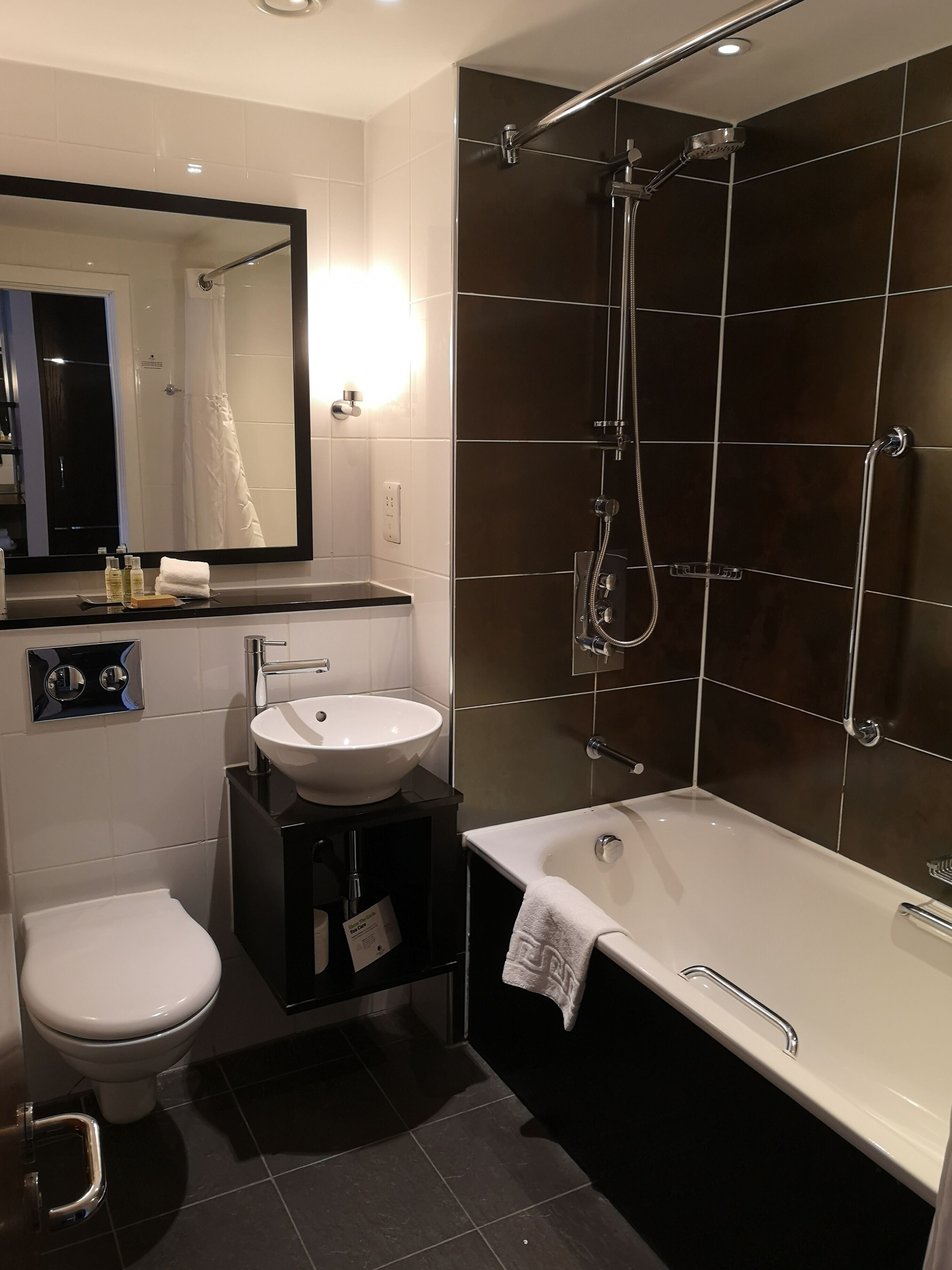 A modern bathroom with a white sink, a toilet, and a walk-in shower.