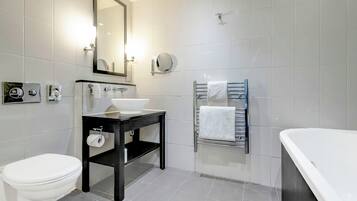 Un baño moderno con inodoro, lavabo, espejo, toallero y bañera.