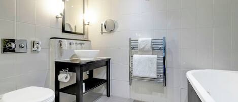 Un bagno moderno con servizi igienici, lavandino, specchio, portasciuga e vasca da bagno.