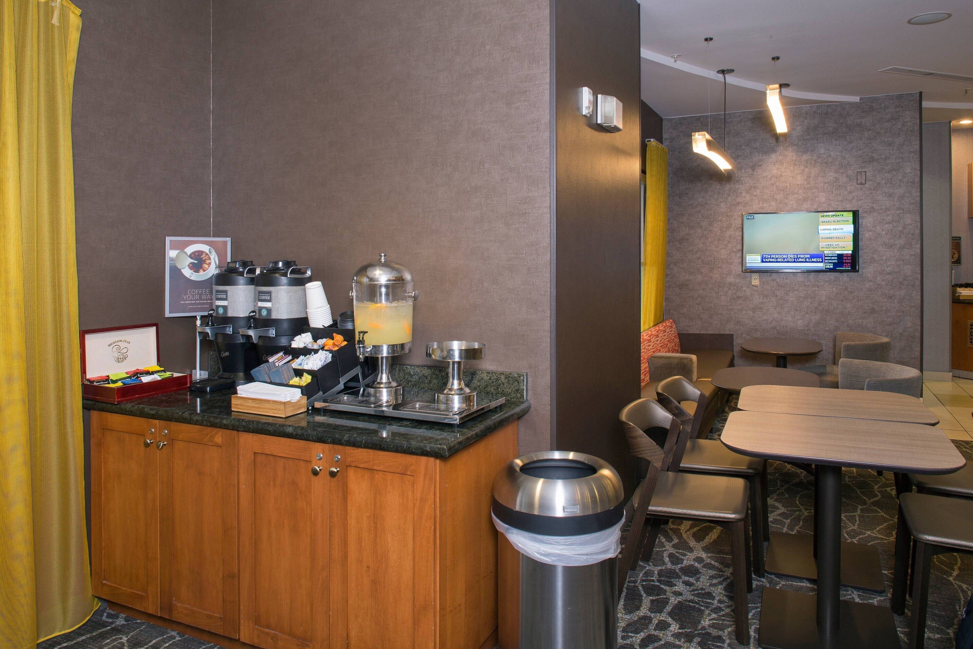 Une chambre d’hôtel équipée d’une kitchenette, d’un téléviseur fixé au mur et d’un coin salon avec tables et chaises.