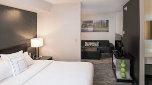 A hotel room with a large bed, a desk with a lamp, a television, and a small seating area with cushions. - Springhill Suites by Marriott Billings (Billings)