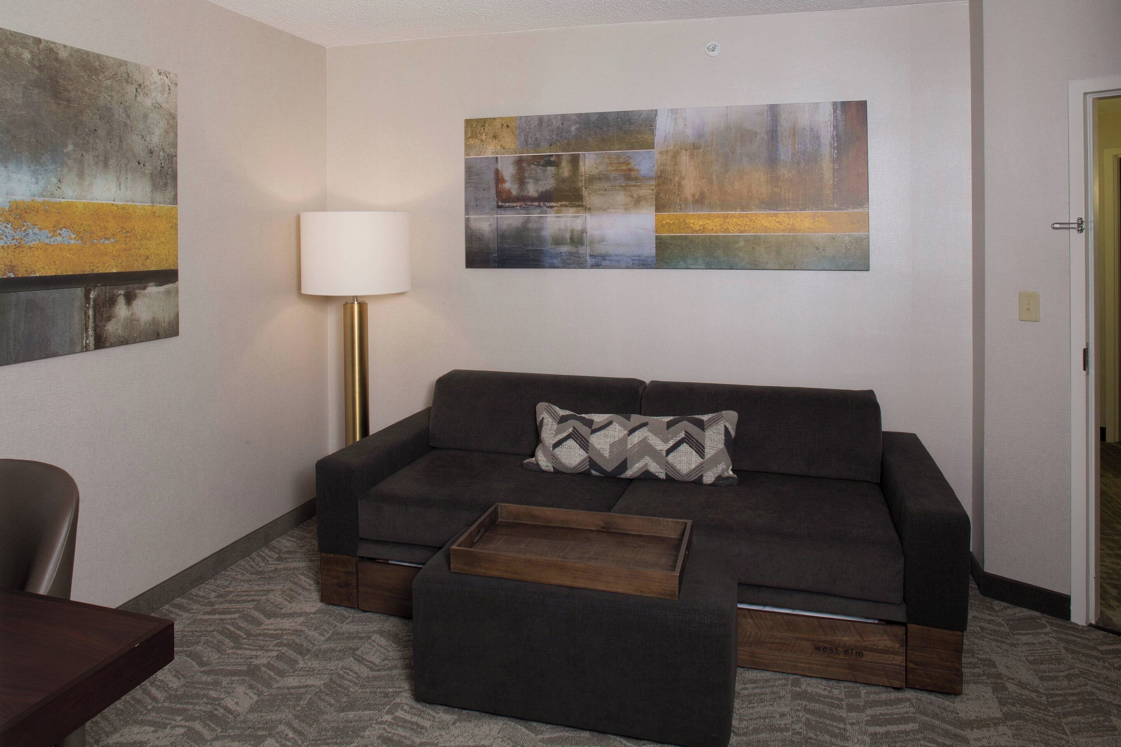 A modern living room with a sectional sofa, a wooden coffee table, and abstract art on the walls.