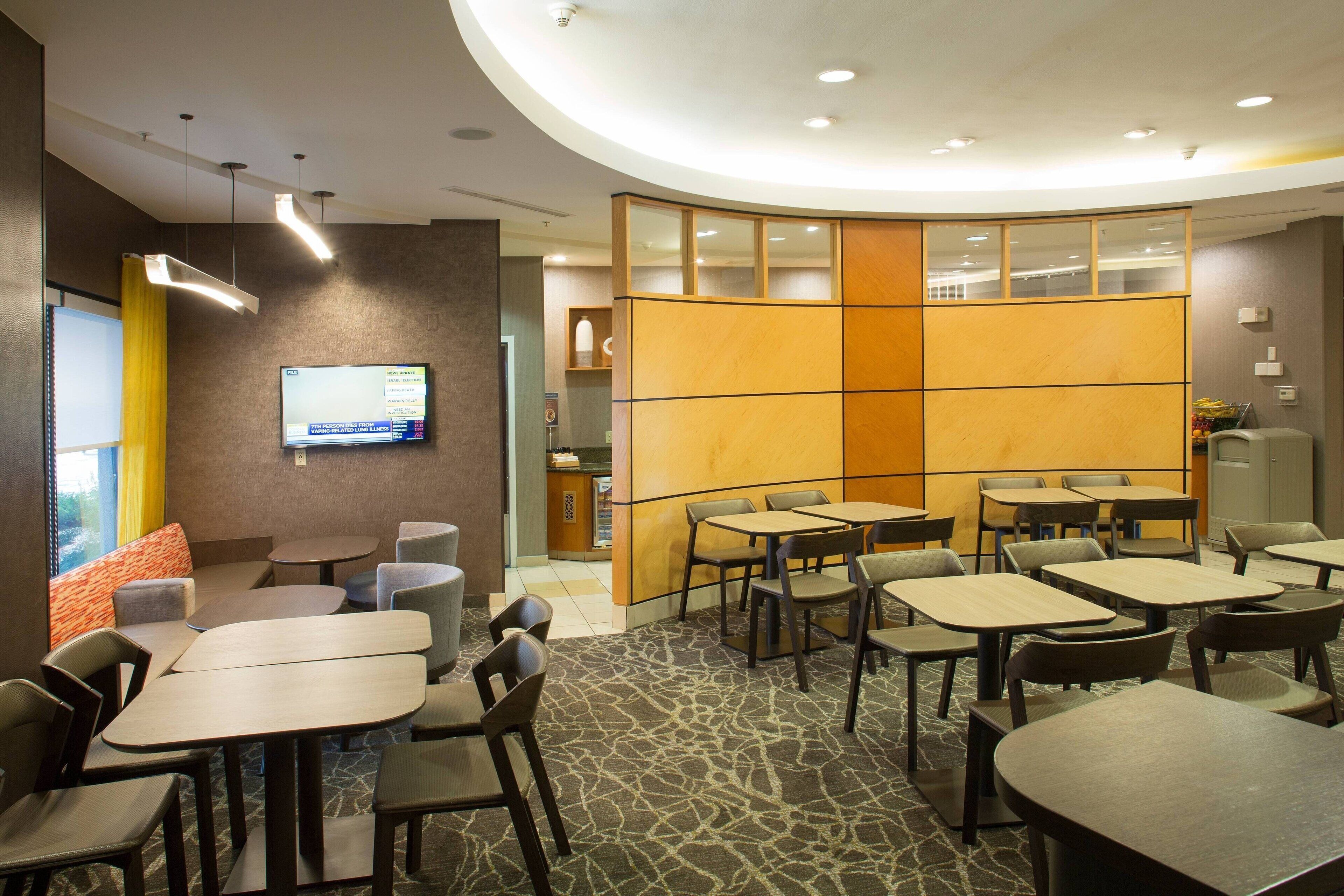 A conference room with tables and chairs, a television screen, and a partition wall.
