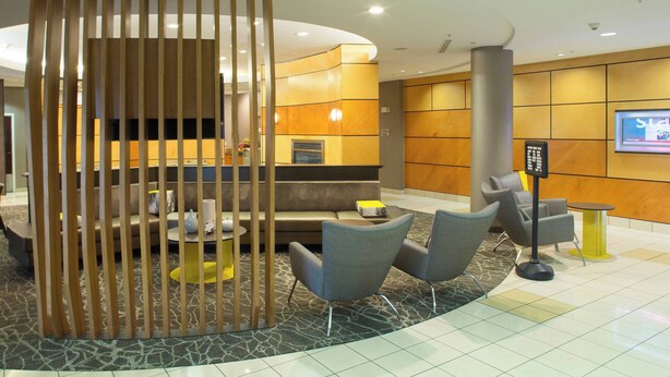 A modern lobby with a seating area, a reception desk, and a television screen. - Springhill Suites by Marriott Billings (Billings)