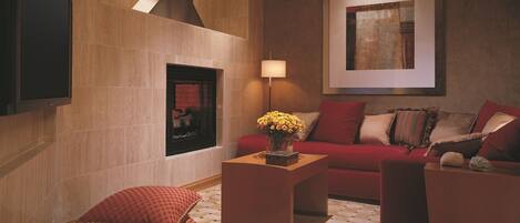 Una sala de estar moderna con chimenea, un sofá rojo, una mesa de centro y una obra de arte enmarcada en la pared.