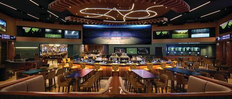 A sports bar with multiple screens, a bar area, and seating for patrons.