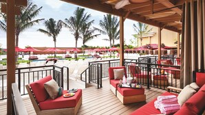 A covered outdoor seating area with red sofas and a pool in the background. - Borgata Hotel Casino & Spa (Atlantic City)