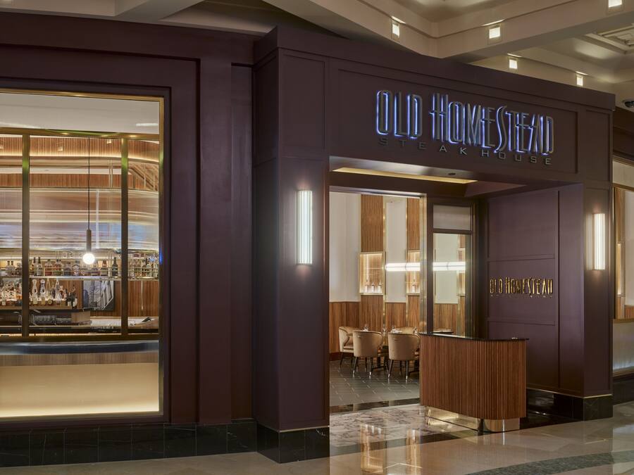 A modern hotel entrance with a sign reading "Old Homestead Steak House."