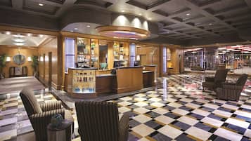 A lobby with a checkered floor, a reception desk, and wicker chairs.