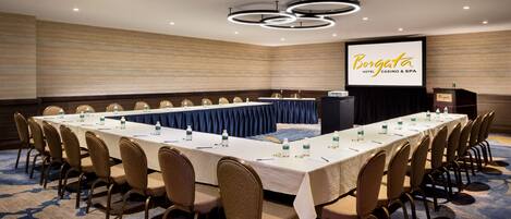 A conference room with a long table, chairs, and a projector screen displaying 'Borgata Hotel & Casino'.