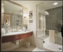 Un baño moderno con encimera de mármol, un espejo grande, cabina de ducha con mampara de vidrio y toallas ordenadas.
