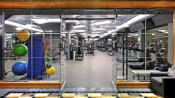 A gym with exercise equipment, a mirrored wall, and a patterned floor.