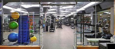 A gym with exercise equipment, a mirrored wall, and a patterned floor.