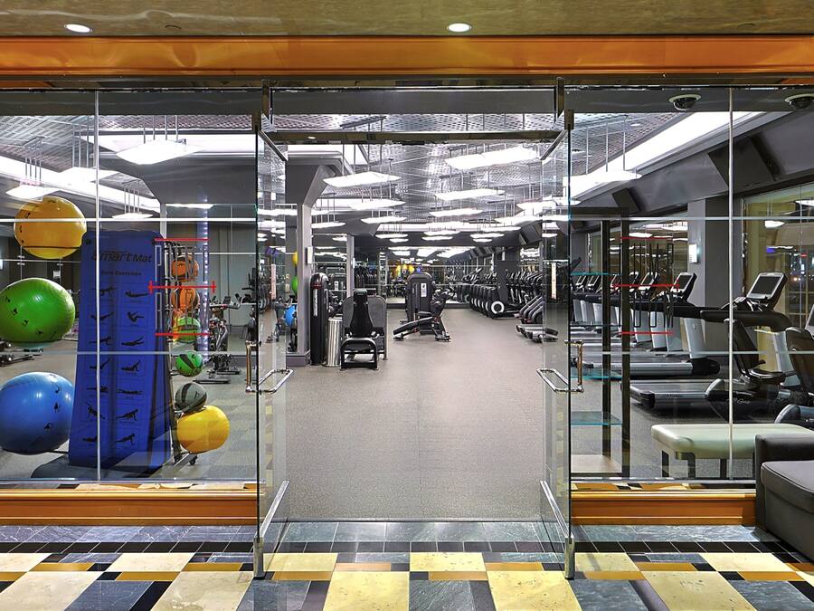 A gym with exercise equipment, a mirrored wall, and a patterned floor.