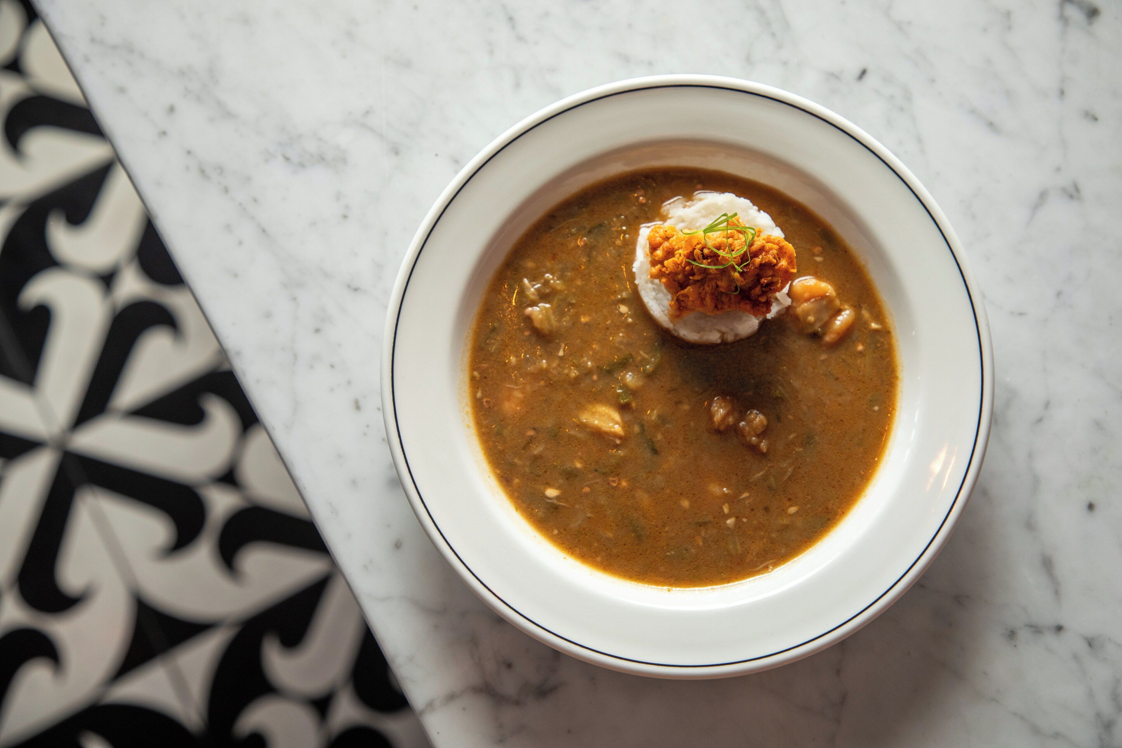 A bowl of soup with a dumpling on a white plate.