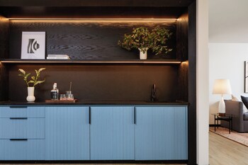 A modern reception area with a long reception desk, seating area with chairs, a sofa, and a coffee table. at Kimpton Hotel Fontenot by IHG