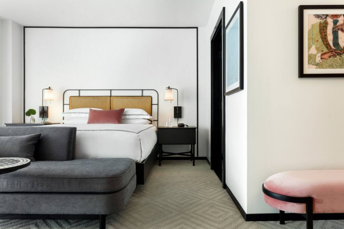 Ein Hotelzimmer mit Bett, Nachttischen, Schreibtisch, Stuhl und einer Couch.