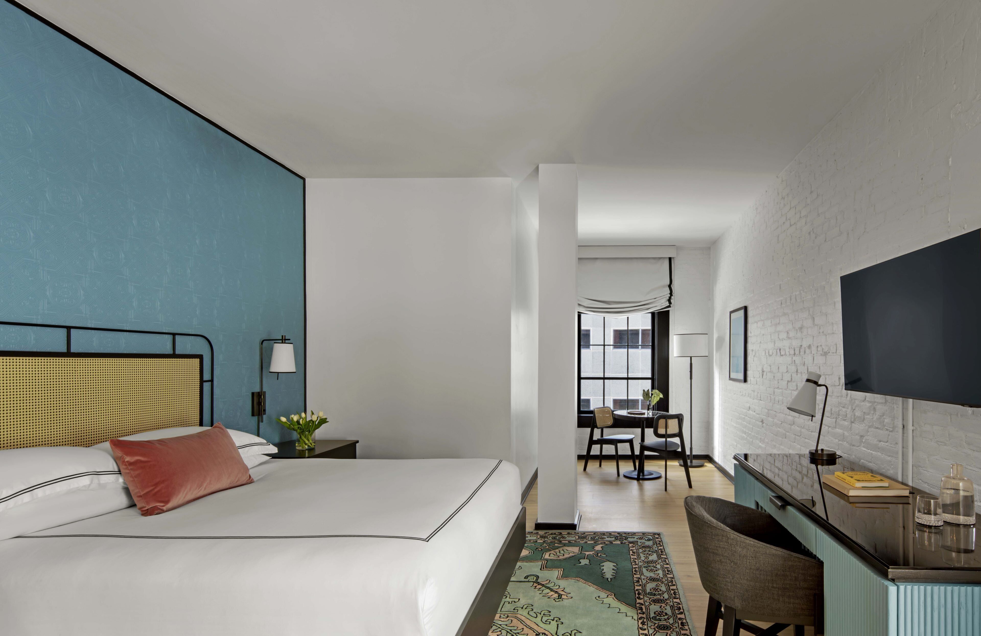 A modern hotel room with a large bed, a desk, and a TV.