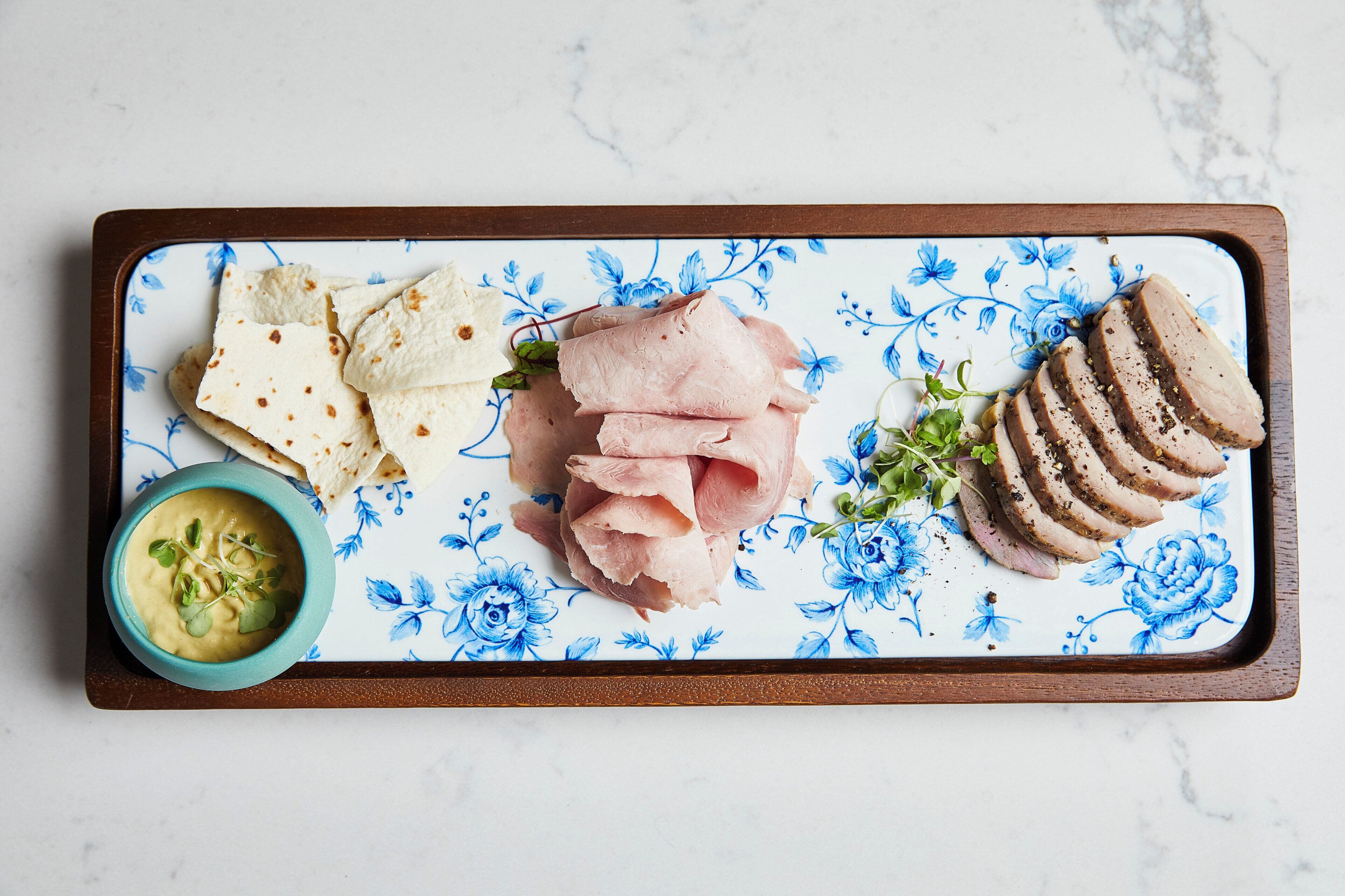 A tray with sliced meat, flatbread, and a bowl of soup.