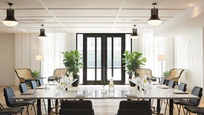 A conference room with a long table, black chairs, and potted plants. - Kimpton Hotel Fontenot by IHG (New Orleans)