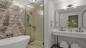 A modern bathroom with a freestanding bathtub, a glass-enclosed shower, and a vanity with a large mirror.