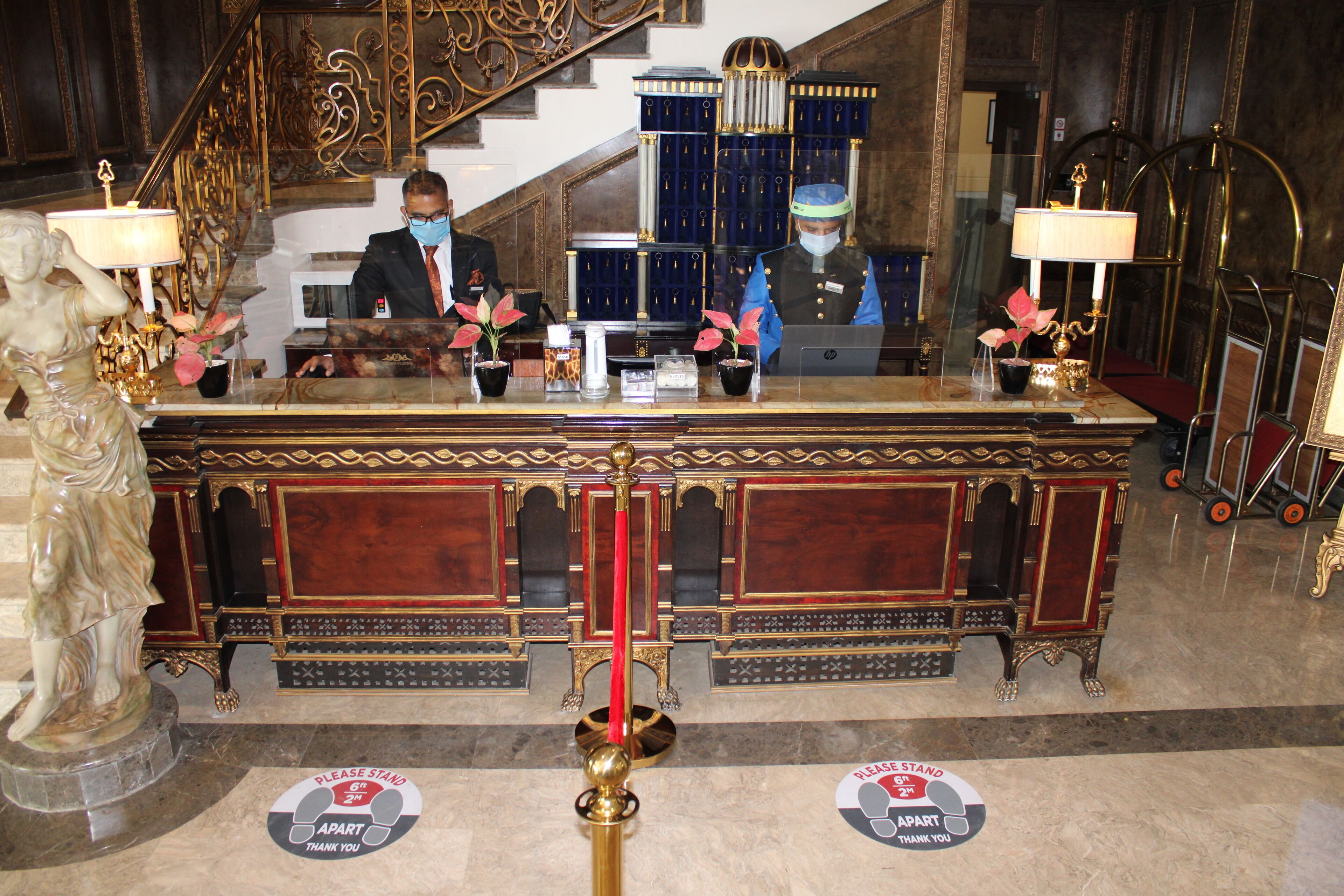 Un comptoir d’accueil avec une statue, un escalier et un meuble bleu en arrière-plan.