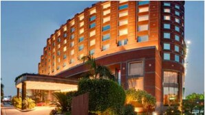 A multi-story hotel with a central courtyard, surrounded by greenery and well-maintained lawns. - Radisson Blu Hotel Noida (Noida)