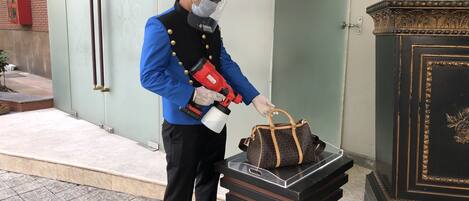 A person in uniform holding a red device and a brown bag, standing next to a black table with a glass top.