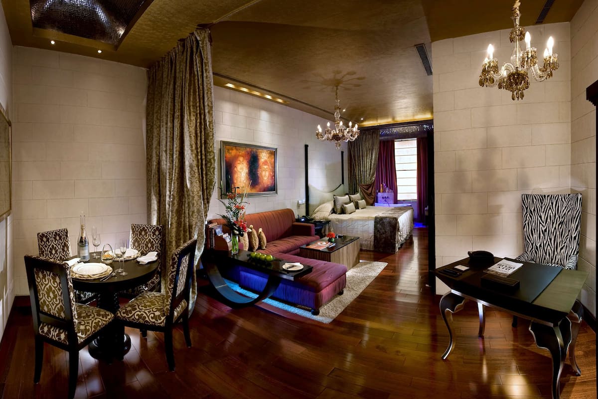 A spacious living room with a round dining table, plush seating, and a chandelier.