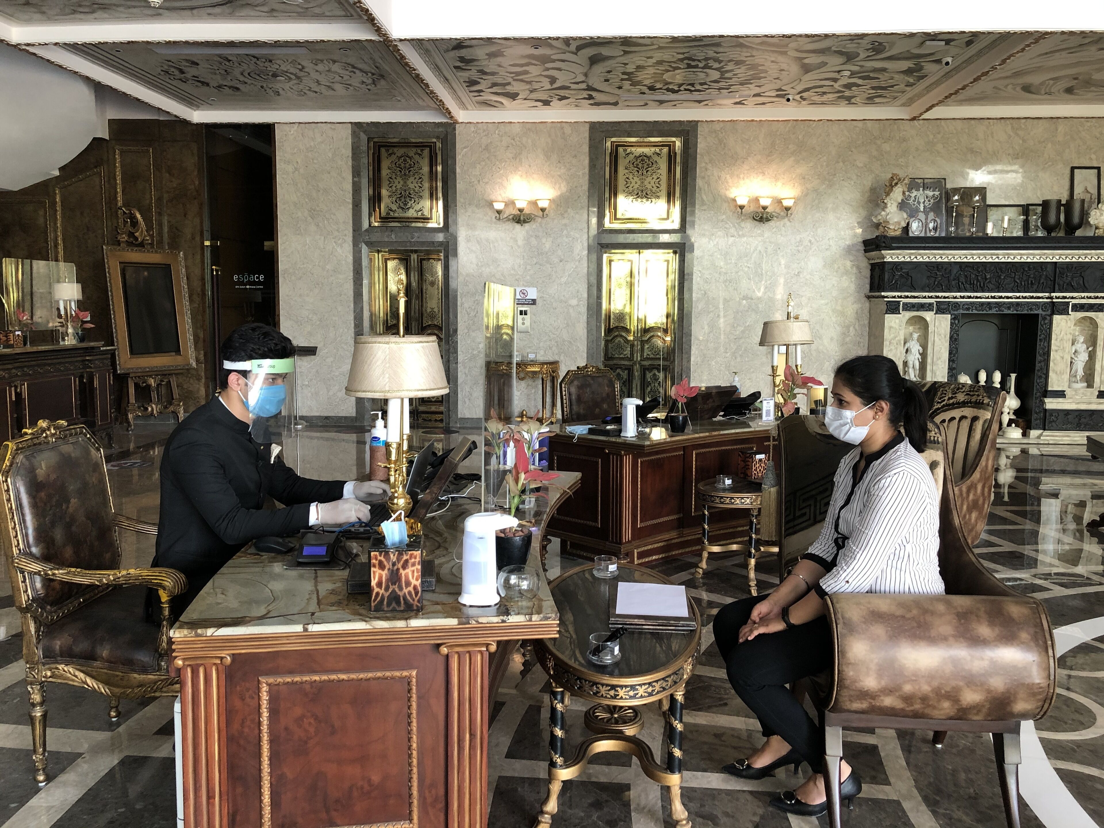 A luxurious lobby with ornate decor, a reception desk, and seating areas.