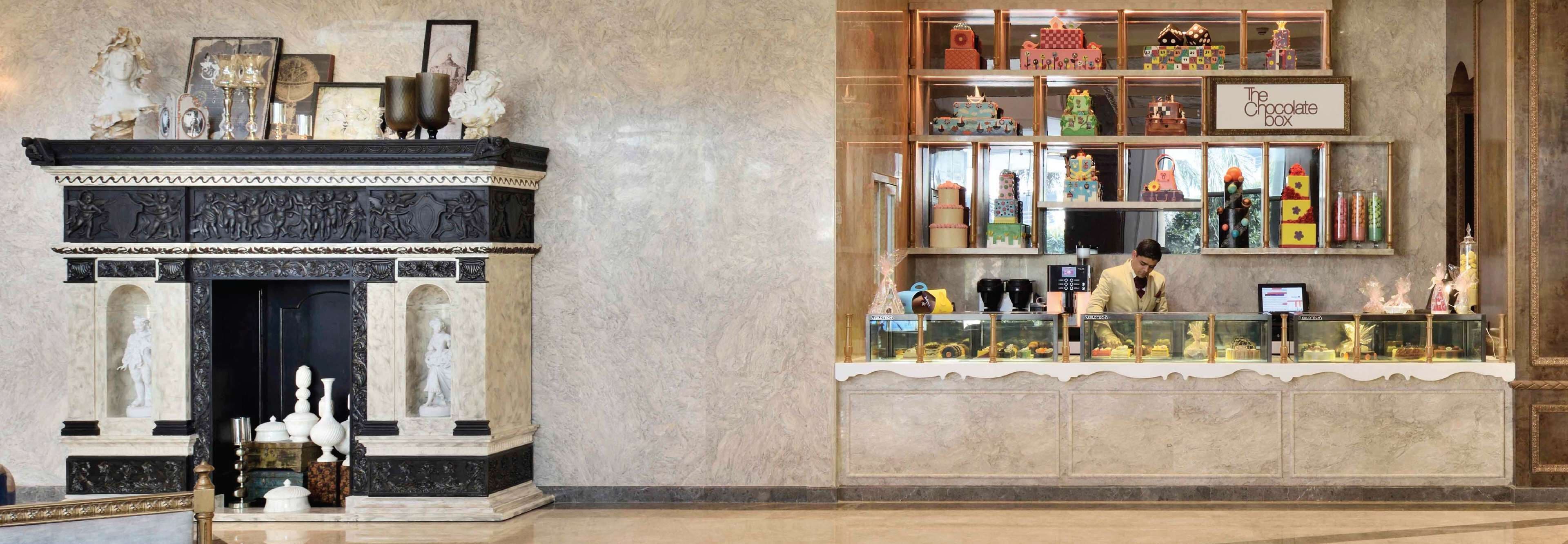A marble fireplace with sculptures and a display case of chocolates.