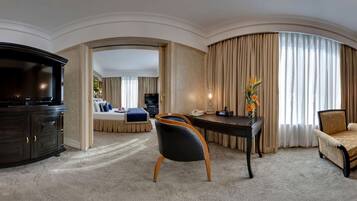 A spacious living room with a large TV, a dining area, and a sofa.