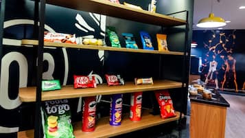 A snack shelf with various brands like Pringles, KitKat, and Doritos.