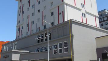 A modern hotel with a flat roof, multiple windows, and a prominent red and white color scheme.