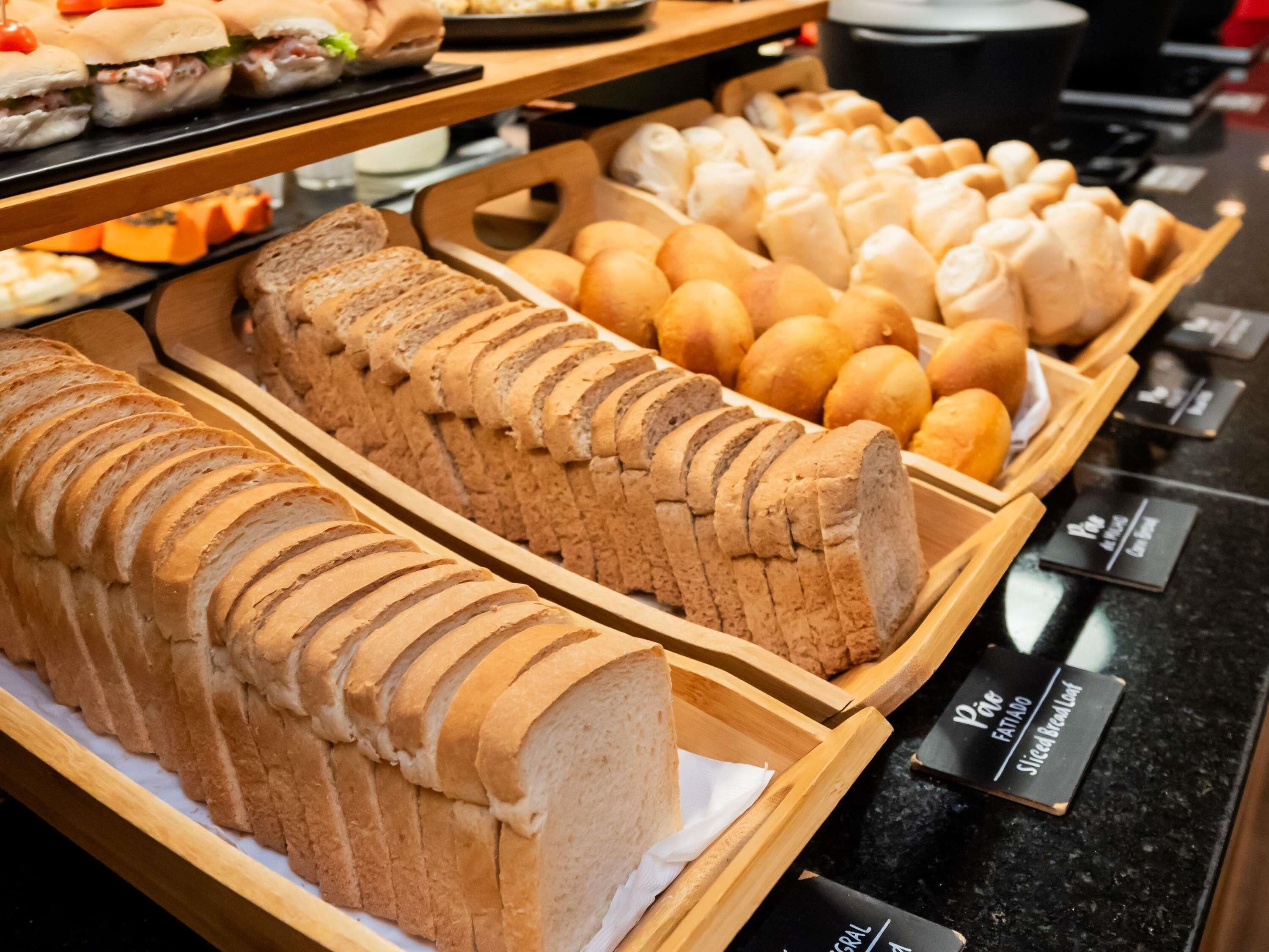 Mostrador de panadería con hogazas de pan y diferentes tipos de panecillos.