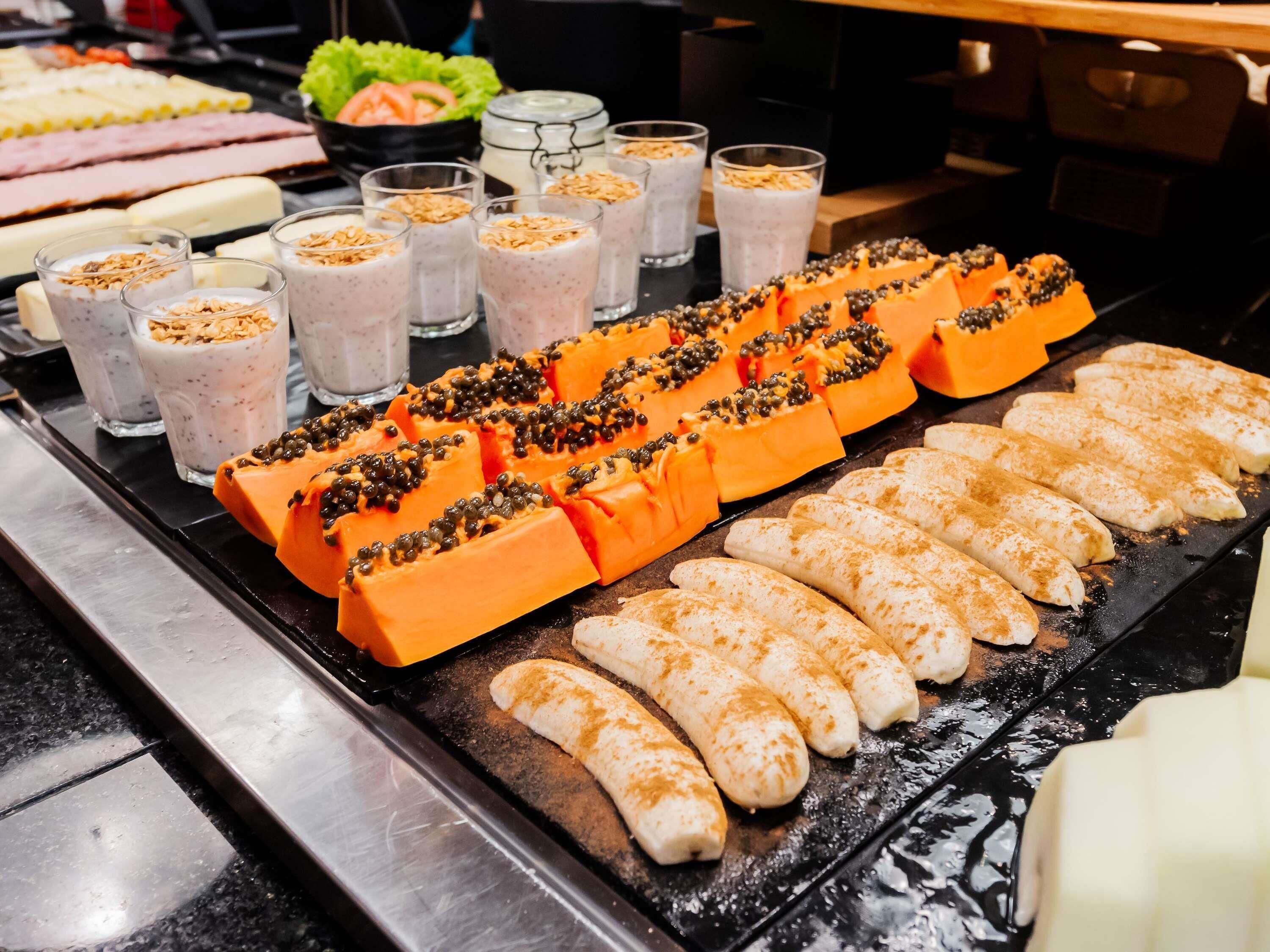 A buffet with various food items including sliced fruits, a selection of beverages, and a variety of dishes.