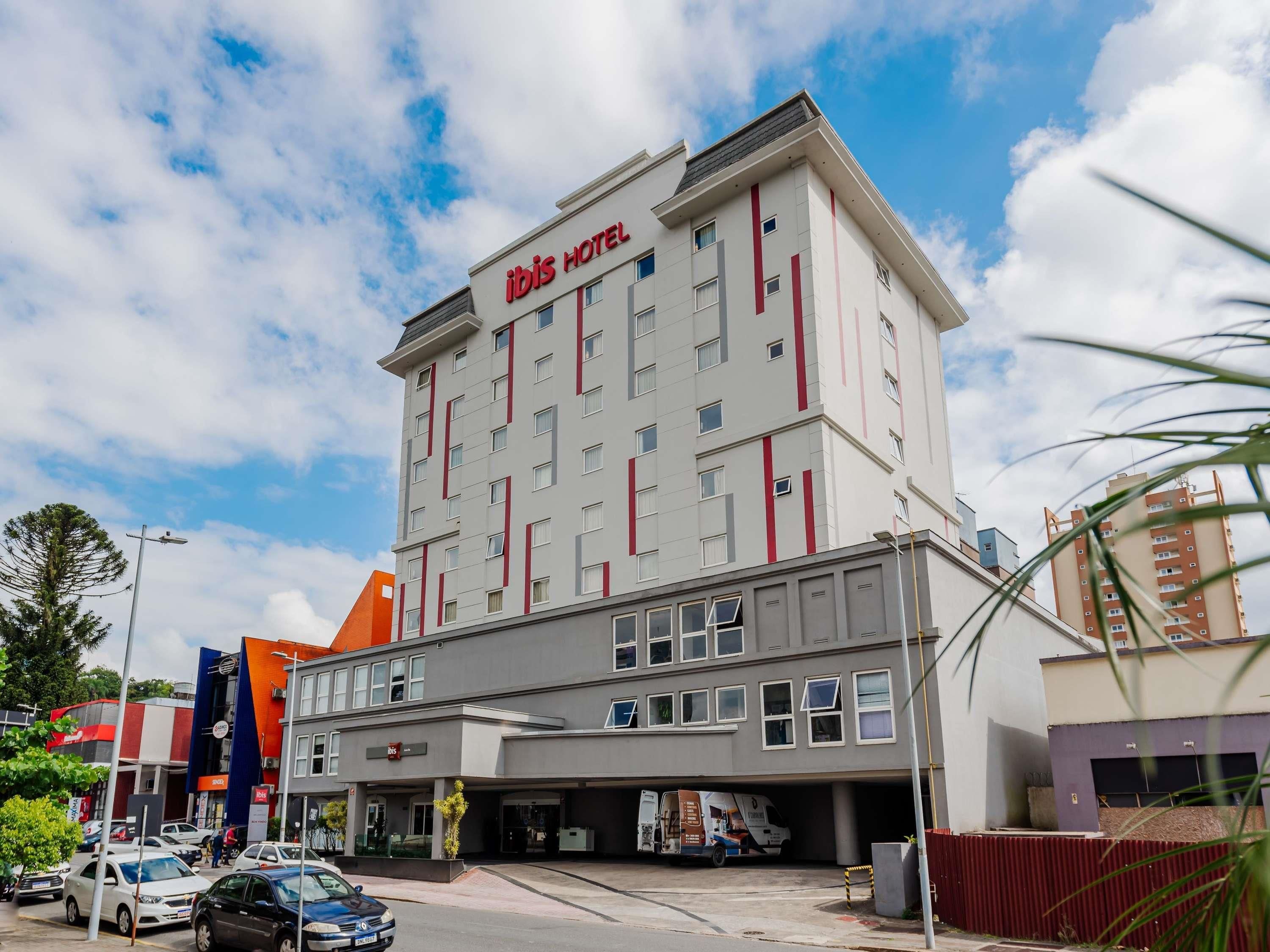 Um hotel com design moderno, exibindo um letreiro chamativo 'ibis HOTEL'.