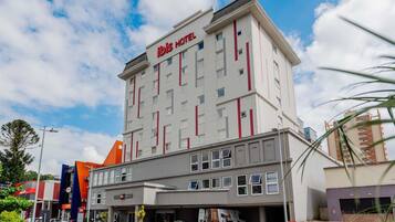 Um hotel com design moderno, exibindo um letreiro chamativo 'ibis HOTEL'.
