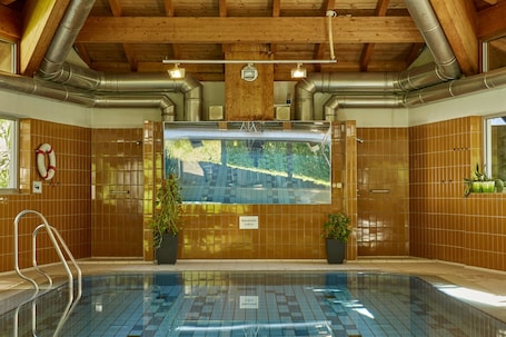 Una piscina techada, sillones reclinables de piscina. HYPERION Hotel Garmisch – Partenkirchen